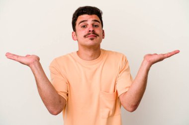 Beyaz arka planda izole edilmiş genç beyaz bir adam. Kafası karışmış ve omuz silkiyor. Kopya alanını tutmak için..