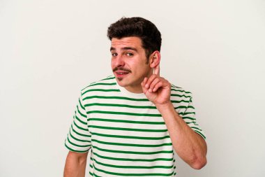 Beyaz arka planda izole edilmiş genç beyaz adam bir dedikoduyu dinlemeye çalışıyor..