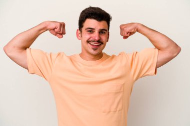 Beyaz arka planda izole edilmiş genç beyaz bir adam güçlü bir hareket gösteriyor, kollarıyla, kadınsı gücün sembolü.