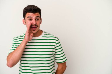 Beyaz arka planda izole edilmiş genç beyaz bir adam gizli bir sıcak fren haberi veriyor ve yana bakıyor.