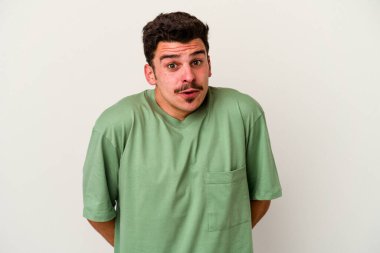 Beyaz arka planda izole edilmiş genç beyaz bir adam omuz silkiyor ve gözleri açık..