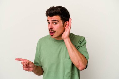 Beyaz arka planda izole edilmiş genç beyaz adam bir dedikoduyu dinlemeye çalışıyor..