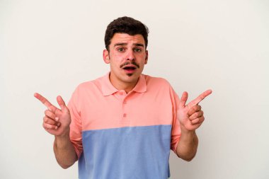 Beyaz arka planda izole edilmiş genç beyaz bir adam farklı kopya alanlarını gösteriyor, birini seçiyor, parmaklarıyla gösteriyor..
