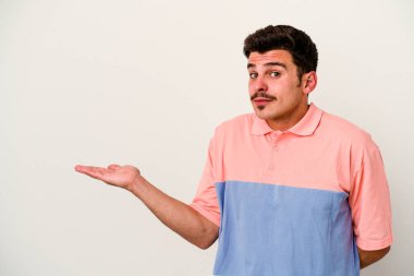 Beyaz arka planda izole edilmiş genç beyaz bir adam bir palmiye üzerinde fotokopi alanı gösteriyor ve belinde başka bir el tutuyor..