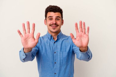 Beyaz arka planda izole edilmiş beyaz tenli genç adam on numarayı elleriyle gösteriyor..