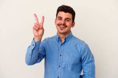 Beyaz arka planda izole edilmiş genç beyaz bir adam neşeli ve kaygısız parmakları olan bir barış sembolü gösteriyor..