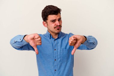 Beyaz arka planda izole edilmiş genç beyaz adam baş parmağını aşağı gösteriyor, hayal kırıklığı konsepti..