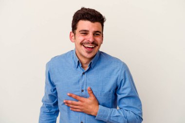 Beyaz arka planda izole genç beyaz adam yüksek sesle gülüyor elini göğsüne koyuyor..