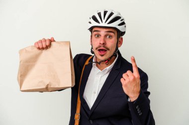 Bisiklet kaskı takan ve elinde tuttuğu genç beyaz arka planda izole edilmiş yiyecekleri alan beyaz bir adam bir fikri, ilham verici bir konsepti var..