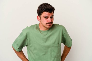 Beyaz arka planda soyutlanmış genç beyaz bir adam kafası karışmış, şüpheli ve güvensiz hissediyor..