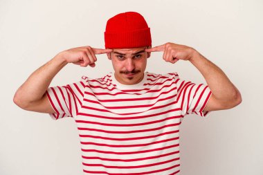 Beyaz arka planda izole edilmiş genç beyaz bir adam bir göreve odaklanmış, işaret parmaklarını işaret ediyor..