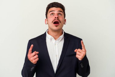 Beyaz arka planda izole edilmiş kablosuz kulaklık takan beyaz iş adamı ağzı açık bir şekilde yukarı bakıyor..