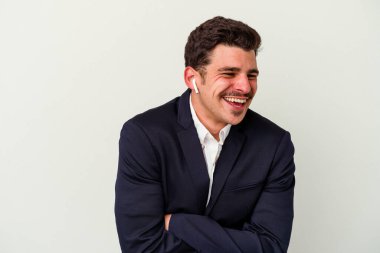 Beyaz arka planda izole edilmiş kablosuz kulaklık takan beyaz iş adamı gülüyor ve eğleniyor..