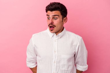 Pembe arka planda izole edilmiş genç beyaz adam gördüğü bir şey yüzünden şoka uğruyor..