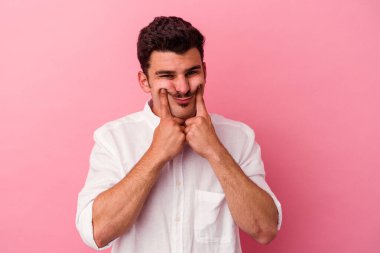 Pembe arka planda izole edilmiş beyaz bir adam iki seçenek arasında şüphe duyuyor..