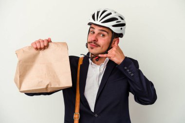 Bisiklet kaskı takan ve elinde tuttuğu beyaz arka planda izole edilmiş yiyecek taşıyan genç beyaz bir adam cep telefonu hareketini parmaklarıyla gösteriyor..