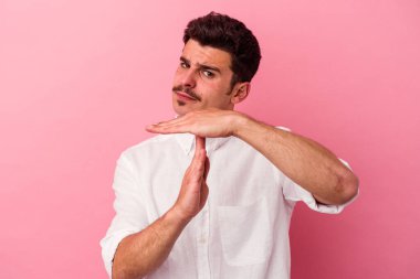 Pembe arka planda izole edilmiş genç beyaz adam bir mola hareketi gösteriyor..