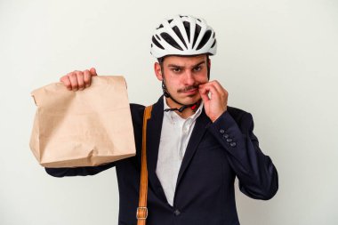 Bisiklet kaskı takan ve elinde tuttuğu beyaz arka planda izole edilmiş yiyecekleri saklayan beyaz iş adamı..