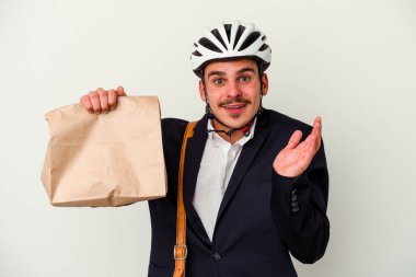 Bisiklet kaskı takan ve elinde tuttuğu genç beyaz arka planda izole edilmiş yiyecekleri alan beyaz bir adam şaşırmış ve şok olmuştu..