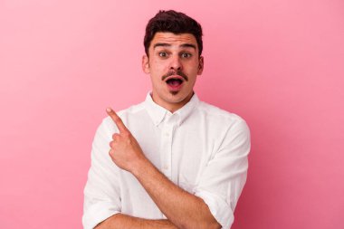 Pembe arka planda izole edilmiş genç beyaz adam yan tarafı gösteriyor.
