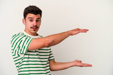 Beyaz arka planda izole edilmiş genç beyaz adam elleri arasında bir kopya alanı tutarken şok ve hayrete düştü..