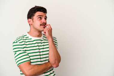 Beyaz arka planda izole edilmiş genç beyaz bir adam rahatlamış bir şeyin fotokopi odasına baktığını düşünüyor..