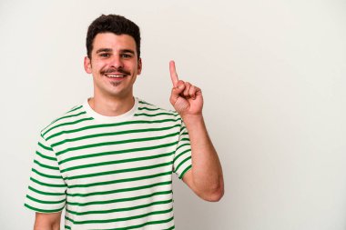 Beyaz arka planda izole edilmiş beyaz tenli genç bir adam bir numarayı parmağıyla gösteriyor..