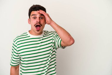 Beyaz arka planda izole genç beyaz adam yüksek sesle bağırıyor, gözleri açık ve elleri gergin tutuyor..