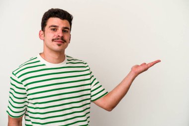 Beyaz arka planda izole edilmiş genç beyaz bir adam bir palmiye üzerinde fotokopi alanı gösteriyor ve belinde başka bir el tutuyor..