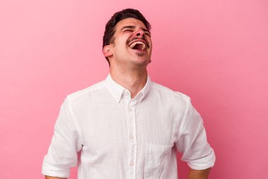 Genç beyaz adam pembe arka planda izole edilmiş rahat ve mutlu bir şekilde gülüyor, boynunda dişlerini gösteriyor..