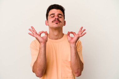 Beyaz arka planda izole edilmiş genç beyaz adam yoğun bir günün ardından rahatlıyor. Yoga yapıyor..