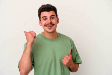 Beyaz arka planda izole edilmiş genç beyaz bir adam iki parmağını da kaldırıyor, gülümsüyor ve kendinden emin..