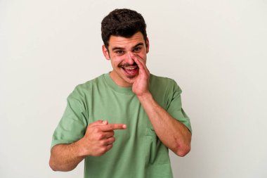 Beyaz arka planda izole edilmiş genç beyaz bir adam bir dedikodu söylüyor, bir haber sunuyor..