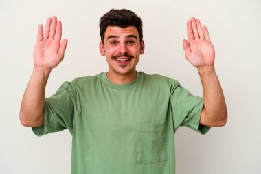 Beyaz arka planda izole genç beyaz adam hoş bir sürpriz alıyor, heyecanlı ve el kaldırıyor..