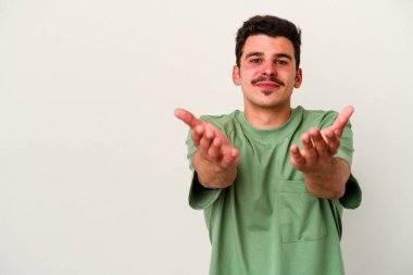 Beyaz arka planda izole edilmiş genç beyaz bir adam dudaklarını katlıyor ve hava öpücüğü vermek için avuç içleri tutuyor..