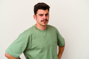 Beyaz arka planda izole edilmiş, hoşnutsuzca kaşlarını çatmış, kollarını kavuşturmuş genç beyaz bir adam..