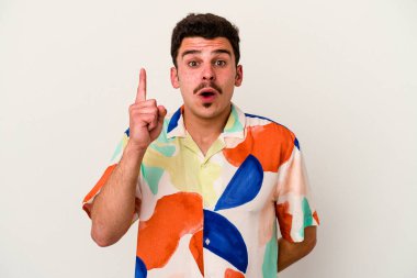 Beyaz arka planda izole edilmiş genç beyaz adam ağzı açık bir şekilde üst tarafı işaret ediyor..