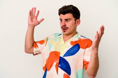 Beyaz arka planda izole edilmiş genç beyaz adam gökyüzüne haykırıyor, yukarı bakıyor, hayal kırıklığına uğramış..