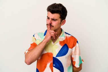 Beyaz arka planda izole edilmiş genç beyaz bir adam ya sır saklıyor ya da sessizlik istiyor..