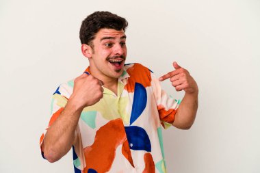 Beyaz arka planda izole edilmiş genç beyaz bir adam parmağını göstererek şaşırdı, geniş bir gülümsemeyle..