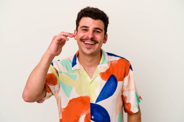 Beyaz arka planda izole olmuş genç beyaz bir adam bir şeye gülüyor, ağızlarını ellerle kapatıyor..