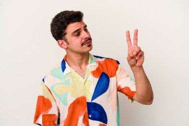 Beyaz arka planda izole edilmiş genç beyaz bir adam neşeli ve kaygısız parmakları olan bir barış sembolü gösteriyor..