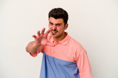Beyaz arka planda izole edilmiş genç beyaz bir adam pençelerini kedi taklidi yaparken gösteriyor, agresif bir hareket..