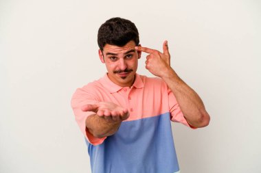 Beyaz arka planda izole edilmiş genç beyaz bir adam elinde bir ürün tutuyor ve.