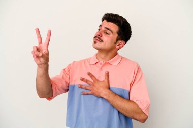 Beyaz arka planda izole edilmiş genç beyaz adam yemin ediyor, elini göğsüne koyuyor..