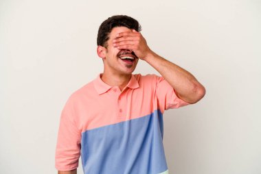 Beyaz arka planda izole olmuş genç beyaz bir adam ellerini başının üstünde tutarak neşeyle gülüyor. Mutluluk kavramı.