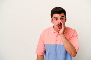 Beyaz arka planda izole edilmiş genç beyaz bir adam gizli bir sıcak fren haberi veriyor ve yana bakıyor.