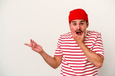 Beyaz arka planda izole edilmiş genç beyaz bir adam bir avuç içinde fotokopi alanı tutuyor, el üstünde tutuyor. Şaşırmış ve mutlu..