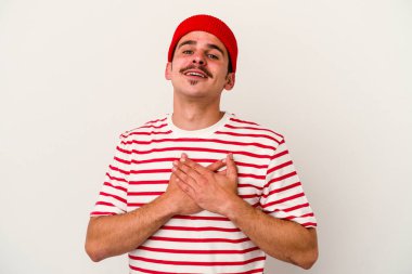 Beyaz arka planda izole edilmiş beyaz tenli genç bir adam, dostane bir ifadeye sahip, avuçlarını göğsüne bastırıyor. Aşk konsepti.