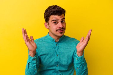 Sarı arka planda izole edilmiş genç beyaz adam şaşırdı ve şok oldu..